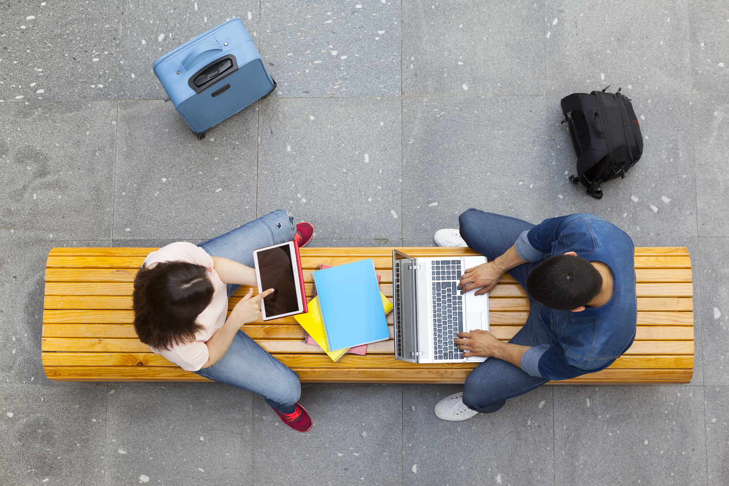Zwei Studierende mit Laptop und Tablet auf einer Bank von oben fotografiert