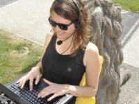 Studentin draußen mit Laptop und Headset