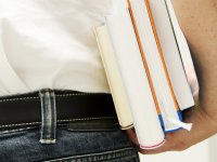 Rückensicht eines Mannes mit Bücherstapel unterm Arm