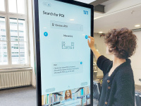 Studentin bedient den Touchscreen des digitalen Leitsystems