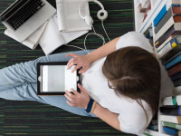 Young woman flipping through her appointment book. She is sitting on the floor leaning against a bookshelf