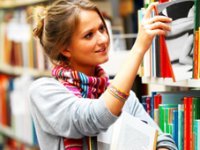 Young woman pulling books from shelf