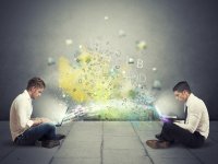 Two students with laptops, a cloud of letters between them