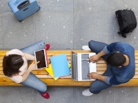 Zwei Studierende mit Laptop und Tablet auf einer Bank von oben fotografiert