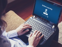 Student in front of notebook with online learning page on the desktop