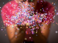 Woman blows confetti from her hand