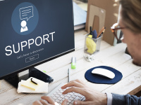 Mann vor einem Laptop, auf dem der Schriftzug Support zu sehen ist