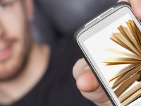 young man presenting smart-phone that shows some books