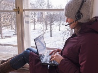 Woman sits with laptop on windowsill 