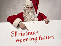 Santa Claus with a sign indicating Christmas opening hours.