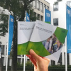 Hand mit Broschüren vor blauen Fahnen der TUM in der Arcisstraße München