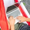 Student mit Laptop in einer Hängematte