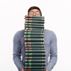 Mann balanciert einen Stapel Bücher