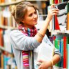 Young woman pulling books from shelf