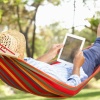 Man with straw hat and tablet relaxing in a hammock