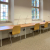 Study desks at a long tabletop in front of windows with stained glass