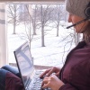 Woman sits with laptop on windowsill