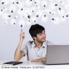 Young man with laptop and notebook who "sees the light". Lots of lightbulbs above his head