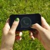 Smartphone with WhatsApp icon on the display, hand-helded by a woman with green nails