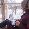 Woman sits with laptop on windowsill 